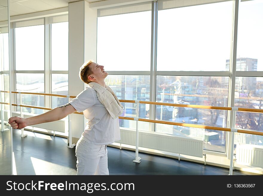 Journalist making successful attempt of standing on hands using ballet barre, tattooed fair-haired guy rejoicing at small win in sport gym. Barefoot boy wearing white T-shirt and trousers. Concept of sportswear, spacious hall or individual trainings. Journalist making successful attempt of standing on hands using ballet barre, tattooed fair-haired guy rejoicing at small win in sport gym. Barefoot boy wearing white T-shirt and trousers. Concept of sportswear, spacious hall or individual trainings