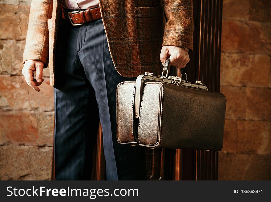 Gentleman in a stylish checkered jacket holds a vintage and a bag. Gentleman in a stylish checkered jacket holds a vintage and a bag