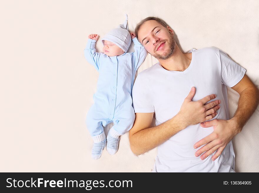 From above shot of handsome men looking at peacefully sleeping baby while lying on soft bed. From above shot of handsome men looking at peacefully sleeping baby while lying on soft bed