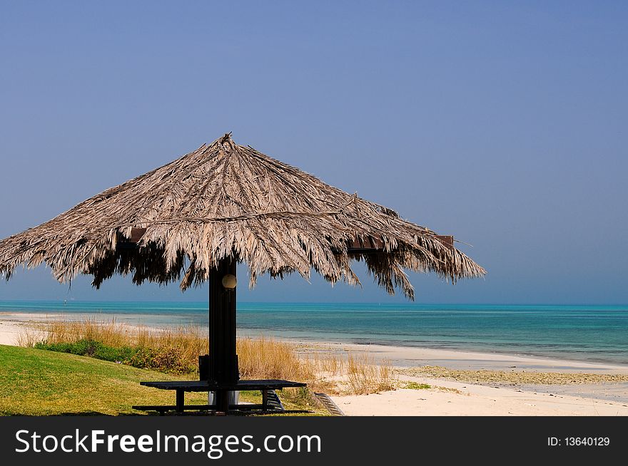 An inviting thatched umbrella on a beautiful tropical beach on the Arabian Gulf.