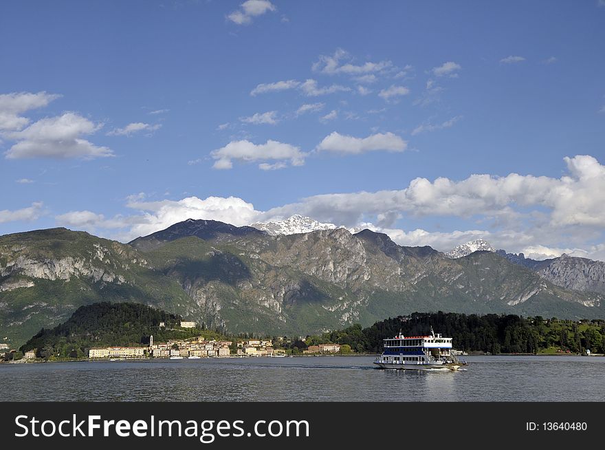 The car ferry crosses Lake Como from Menaggio  to Bellagio with snowy mountains towering in the background. The car ferry crosses Lake Como from Menaggio  to Bellagio with snowy mountains towering in the background