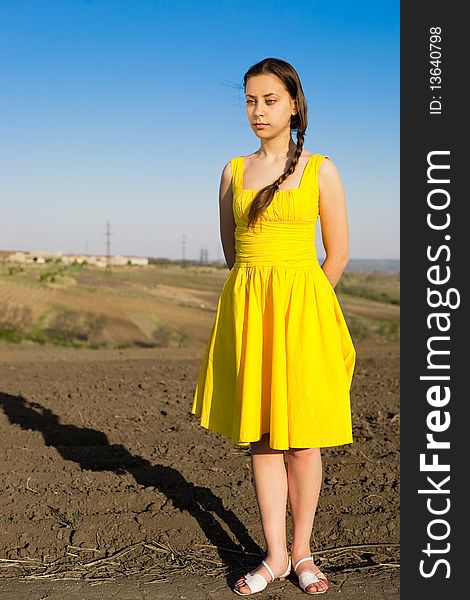 Young woman in a yellow dress, with pigtail in field. Young woman in a yellow dress, with pigtail in field