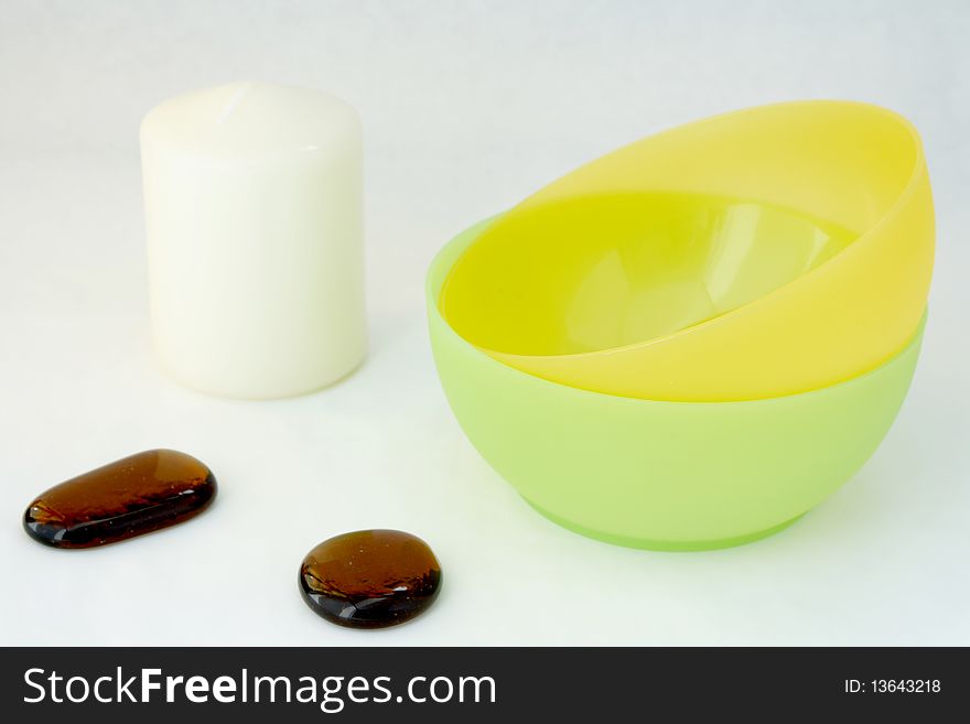 Candle, decorative stones, bowl on the white background