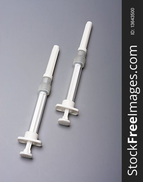 Two syringes on a grey background
