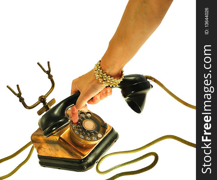 Female hand  with 1940s bracelet dialling vintage telephone made of copper, brass and bakelite, with yellow cable, isolated on white. Female hand  with 1940s bracelet dialling vintage telephone made of copper, brass and bakelite, with yellow cable, isolated on white