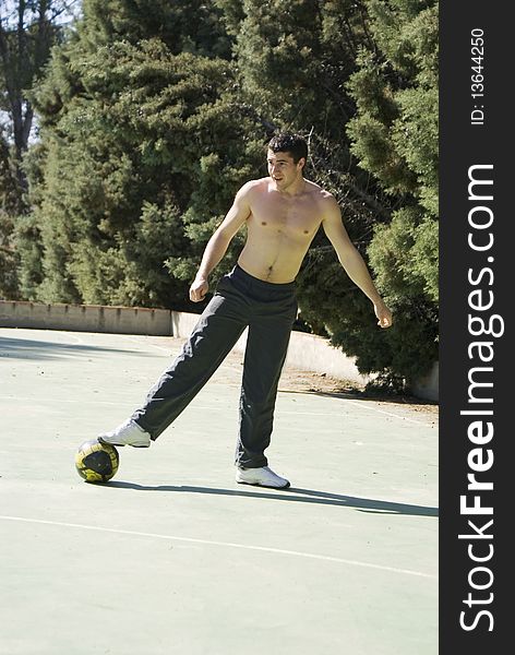 A young man playing football holding his ball with his foot