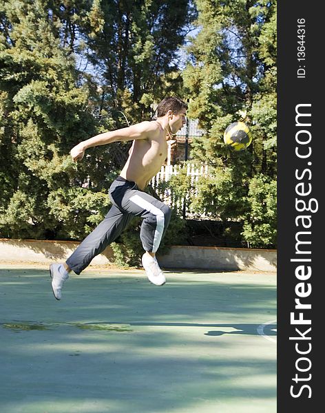 Young man playing football running for his ball