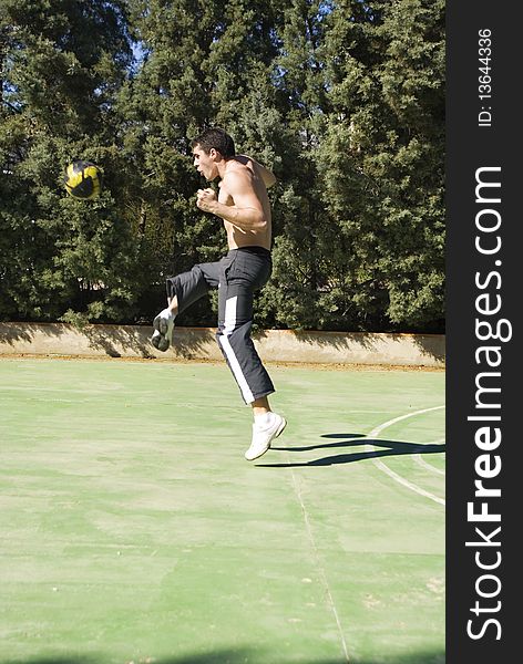 Young man playing football kicking the ball