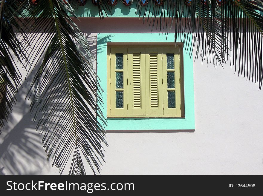 Beautiful tropical colonial style window in pink, green, and yellow with palm leaves. Beautiful tropical colonial style window in pink, green, and yellow with palm leaves