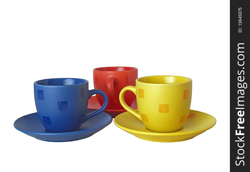 Three cups of different colours with saucers on a white background close up isolated
