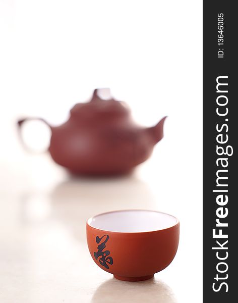 Chinese teacup and pot on marble table. The chinese character 'Tea' is on the teacup.