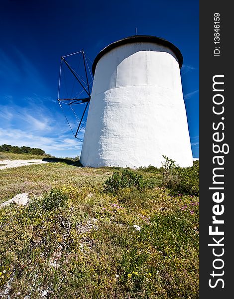 A windmill on a sunny day with beautiful blue skies in the background and green grass and bushes in the foregrond. A windmill on a sunny day with beautiful blue skies in the background and green grass and bushes in the foregrond.