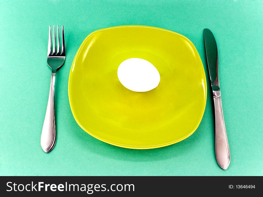 Plate, knife and fork against green background. Plate, knife and fork against green background