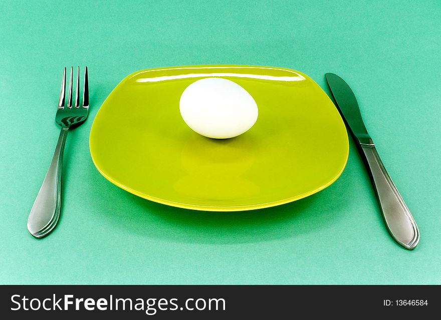 Plate, knife and fork against green background. Plate, knife and fork against green background