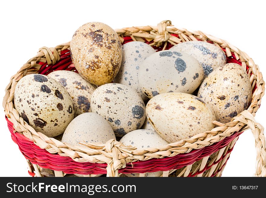 Quail eggs in a straw basket on a white background