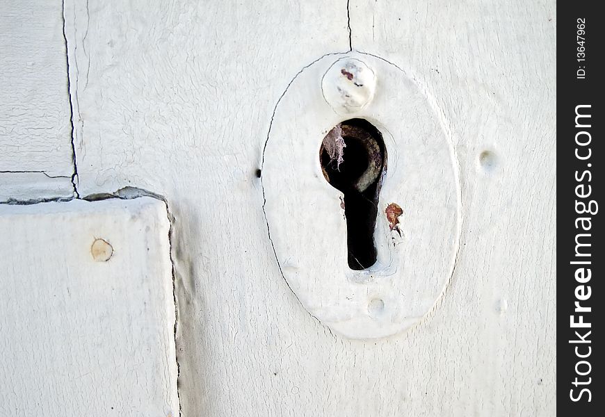 Detail of old white wooden door with keyhole.