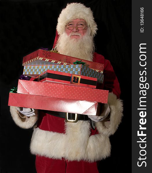 Santa against a black background carrying several gifts. Santa against a black background carrying several gifts.