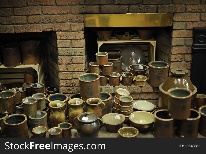 Variety of finished pottery arranged in front of brick fireplace in a kiln room. Horizontal shot. Variety of finished pottery arranged in front of brick fireplace in a kiln room. Horizontal shot.