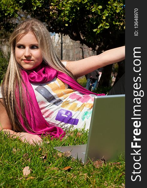 A beautiful attractive blond girl with a laptop in a park. A beautiful attractive blond girl with a laptop in a park
