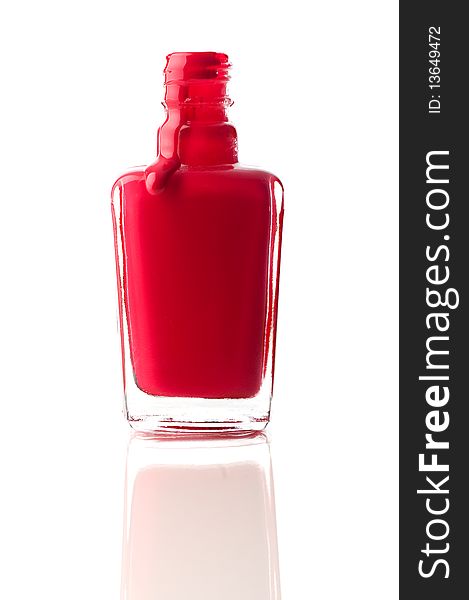 Vertical image of red nail polish running out of a container on a reflective surface