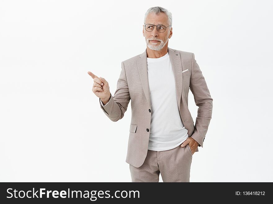 Unretouched shot of good-looking intelligent and elegant old man with grey beard and hair holding hand in pocket