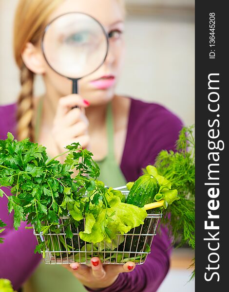 Buying healthy dieting food concept. Woman in kitchen having many green vegetables looking through magnifier at shopping basket trolley. Buying healthy dieting food concept. Woman in kitchen having many green vegetables looking through magnifier at shopping basket trolley