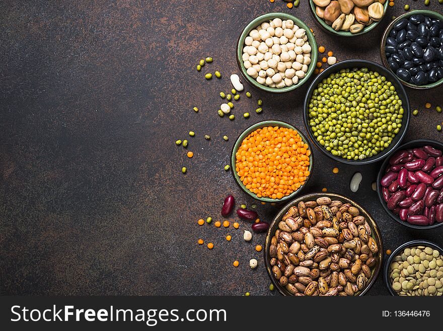 Legumes, lentils, chikpea and beans assortment in different bowls on stone table. Top view with copy space. Legumes, lentils, chikpea and beans assortment in different bowls on stone table. Top view with copy space.