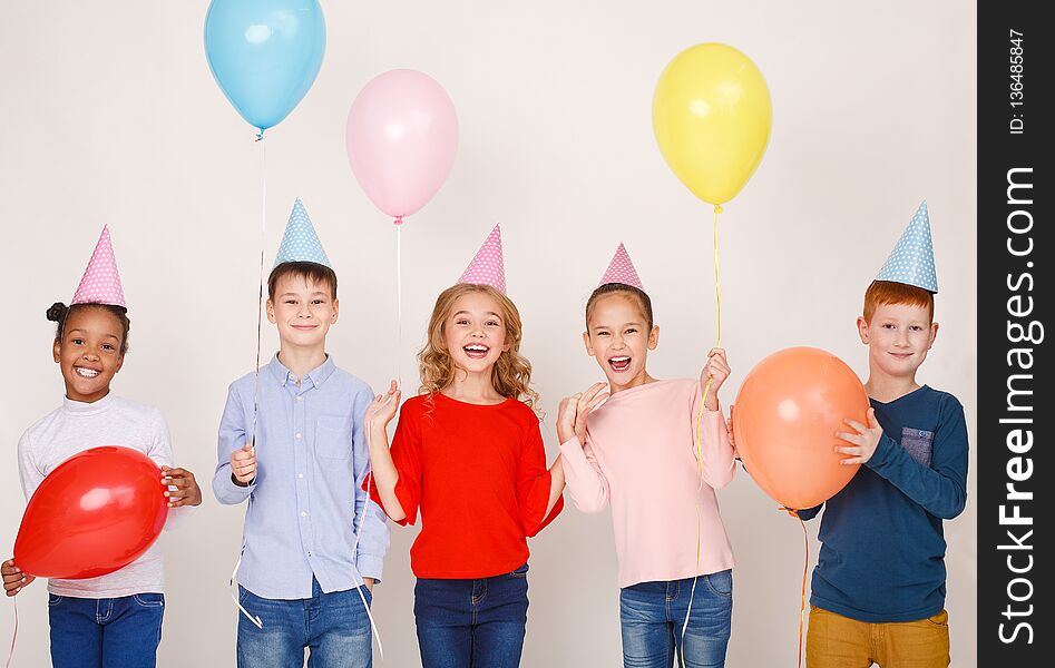 Happy children with colourful balloons posing over light wall. Happy children with colourful balloons posing over light wall