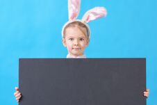 A Child In A White Rabbit Costume On A Blue Background. A Cute Little Girl With Ears Of A Hare Holds In Her Hands An Royalty Free Stock Images