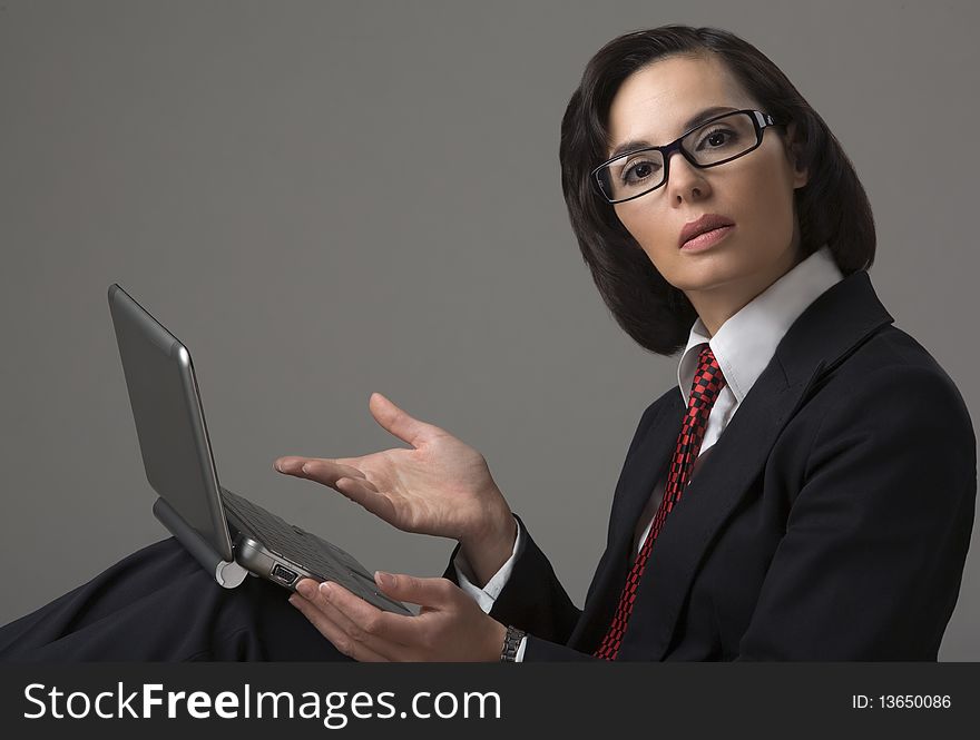 Portrait of the business woman on a grey background with the laptop
