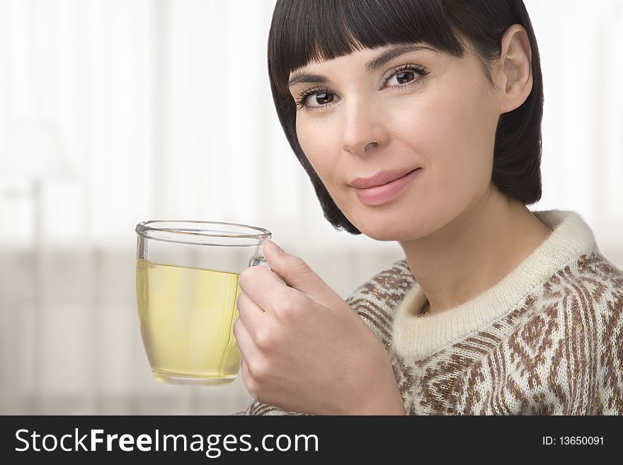 The young woman holds in hand a cup with green tea. The young woman holds in hand a cup with green tea