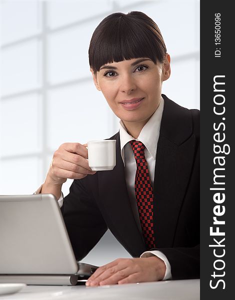 The business woman with a coffee cup in a hand, sits at a computer. The business woman with a coffee cup in a hand, sits at a computer