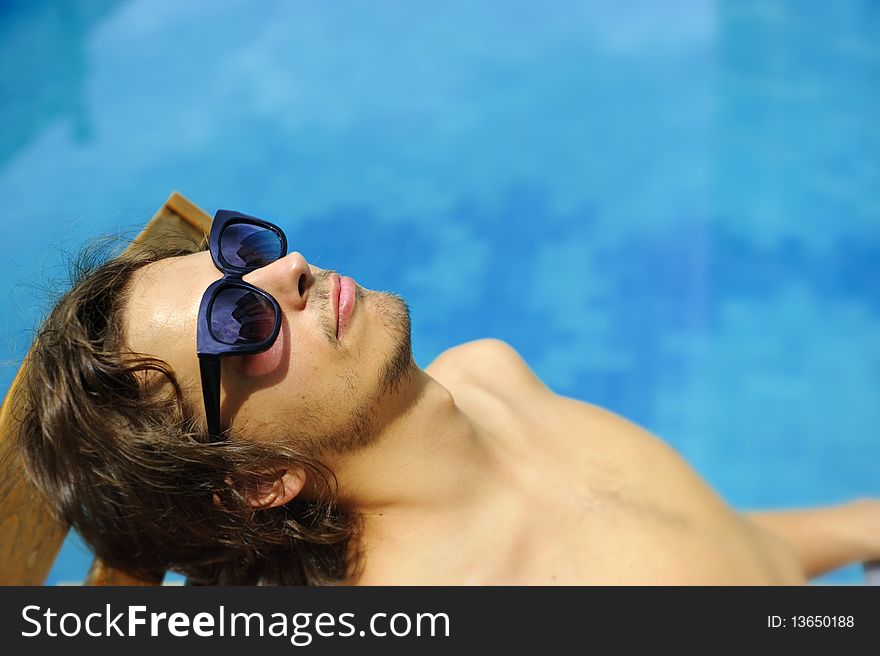 Man tanning poolside on a summer day. Man tanning poolside on a summer day