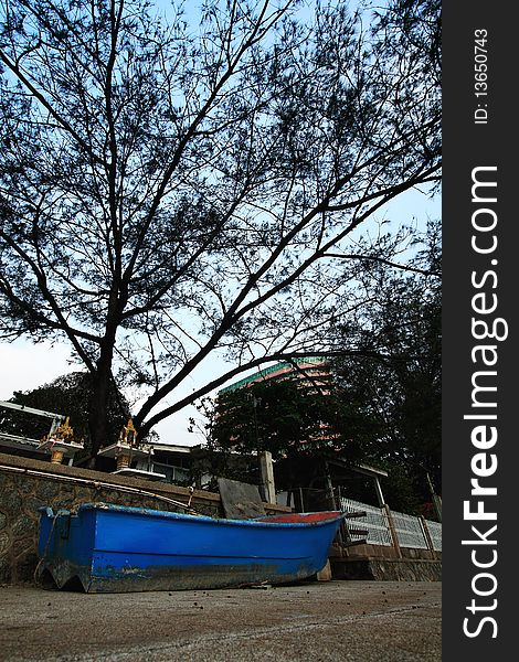 Blue boat on the land under the tree.