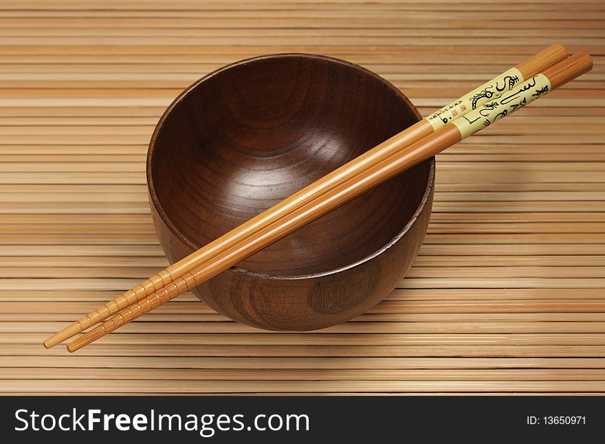 Bowl with chopsticks on the mat background
