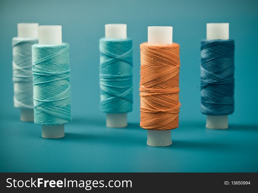 Upright colored spools of thread on a blue background