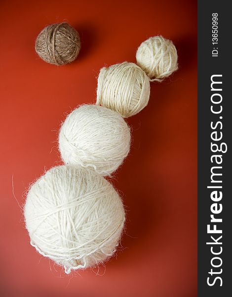 White balls of yarn of various sizes on a red background
