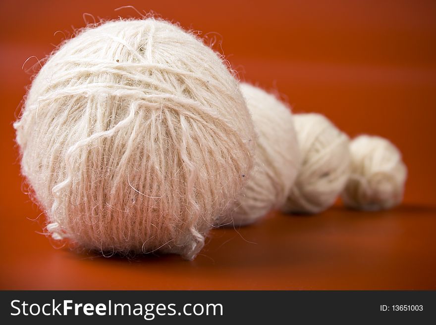 White balls of yarn of various sizes on a red background