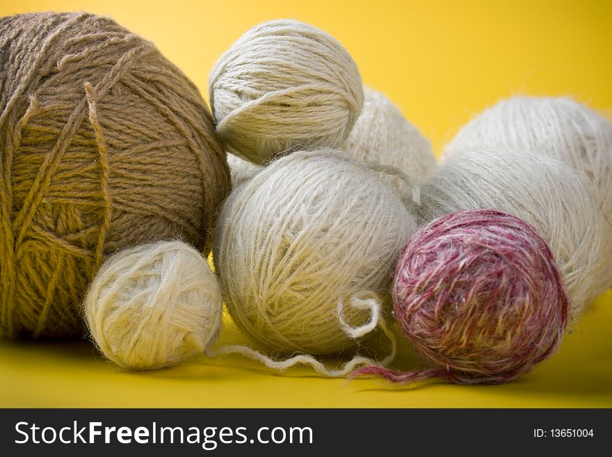 White and brown balls of yarn on a yellow background