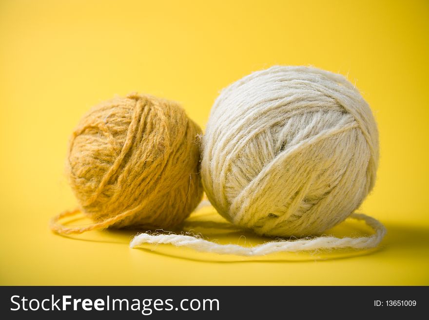 White and yellow balls of yarn on a yellow background