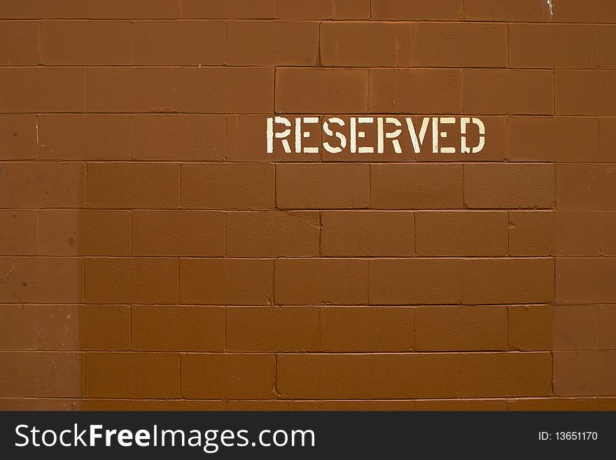 Reserved parking marked on a orange-brown cinderblock wall