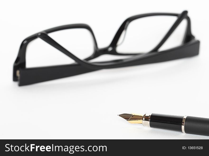 Closeup of fountain pen lying on white background with black spectacles. Closeup of fountain pen lying on white background with black spectacles