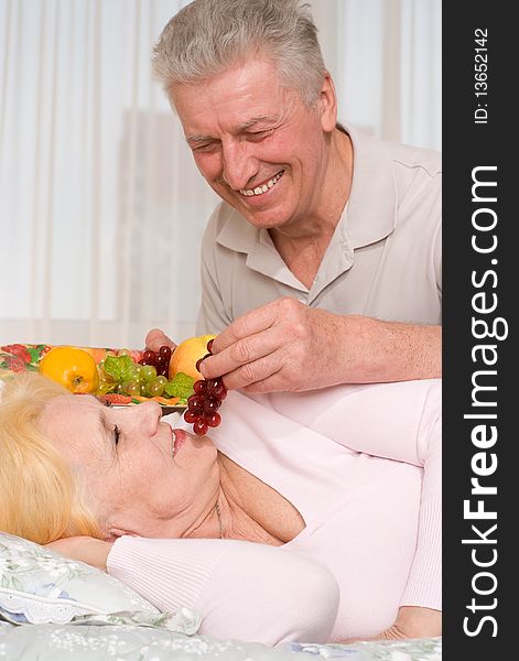 An elderly man brings his wife fruit in bed. An elderly man brings his wife fruit in bed