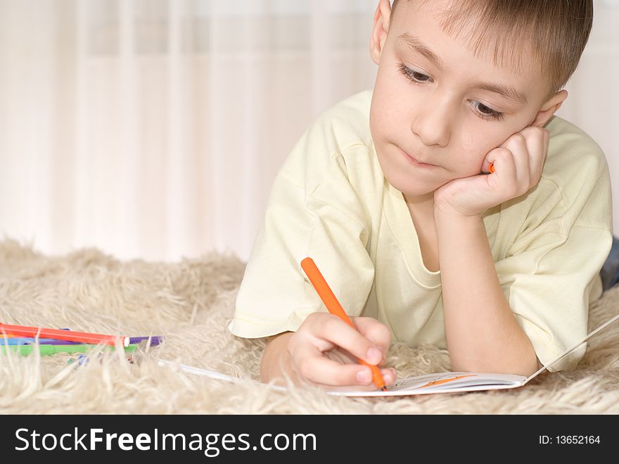 Beautiful boy lying on the carpet and drawing a picture. Beautiful boy lying on the carpet and drawing a picture