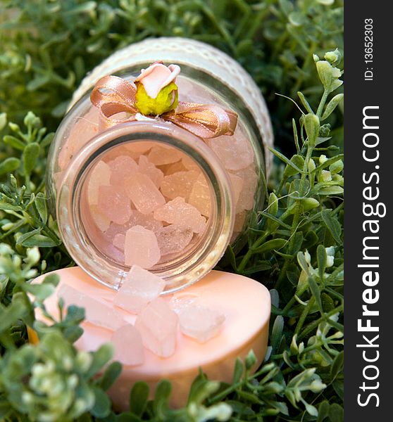 Pink bath salt lies on the green leaves