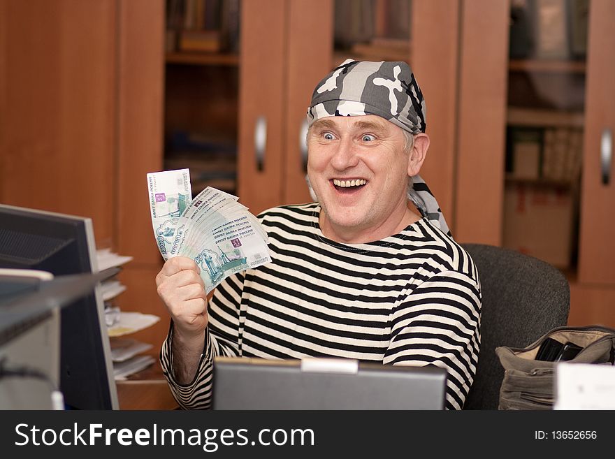 Sailor in headband is laughing with money infront of computer. Sailor in headband is laughing with money infront of computer