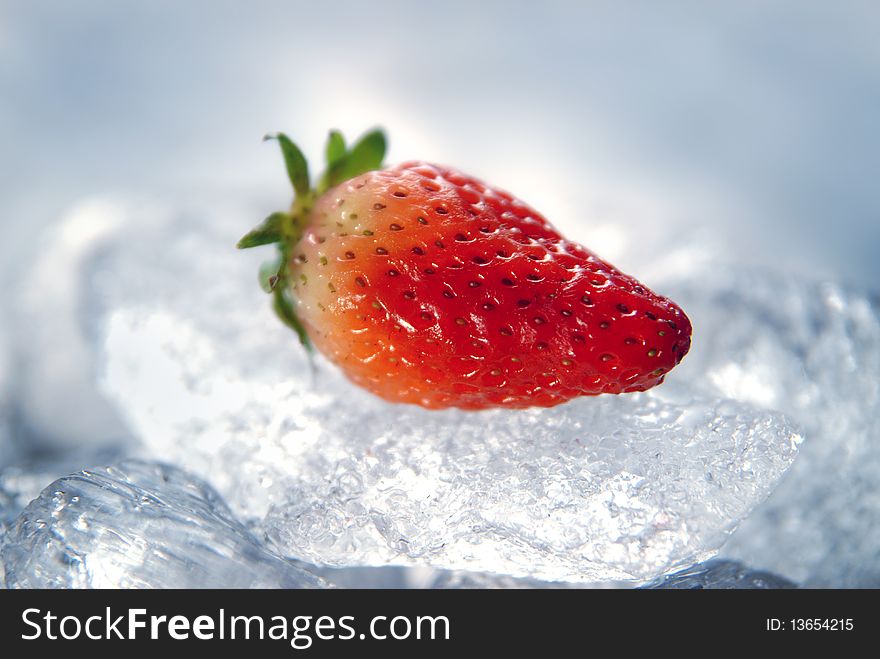 Beautiful bright red strawberry is on large pieces of ice. Beautiful bright red strawberry is on large pieces of ice