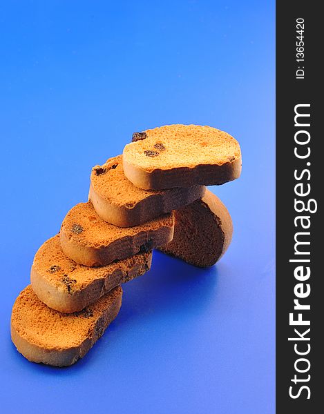 Deep fried bread with raisins lined up in the form of steps in front of blue background. Deep fried bread with raisins lined up in the form of steps in front of blue background