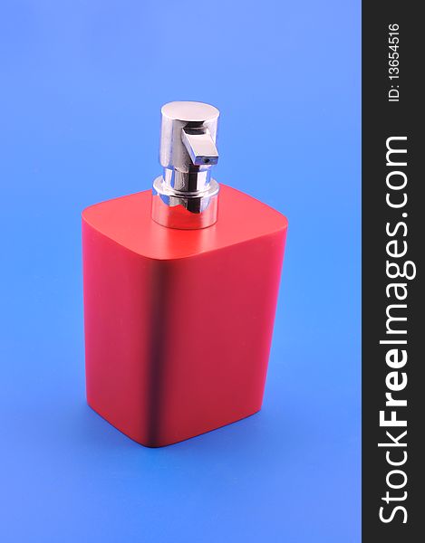 Dispenser for liquid soap red photographed in front of blue background