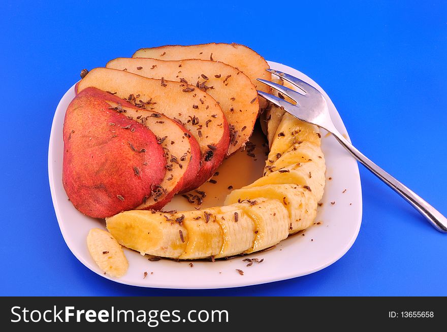 Pear and banana sliced and smothered in syrup in front of blue background. Pear and banana sliced and smothered in syrup in front of blue background